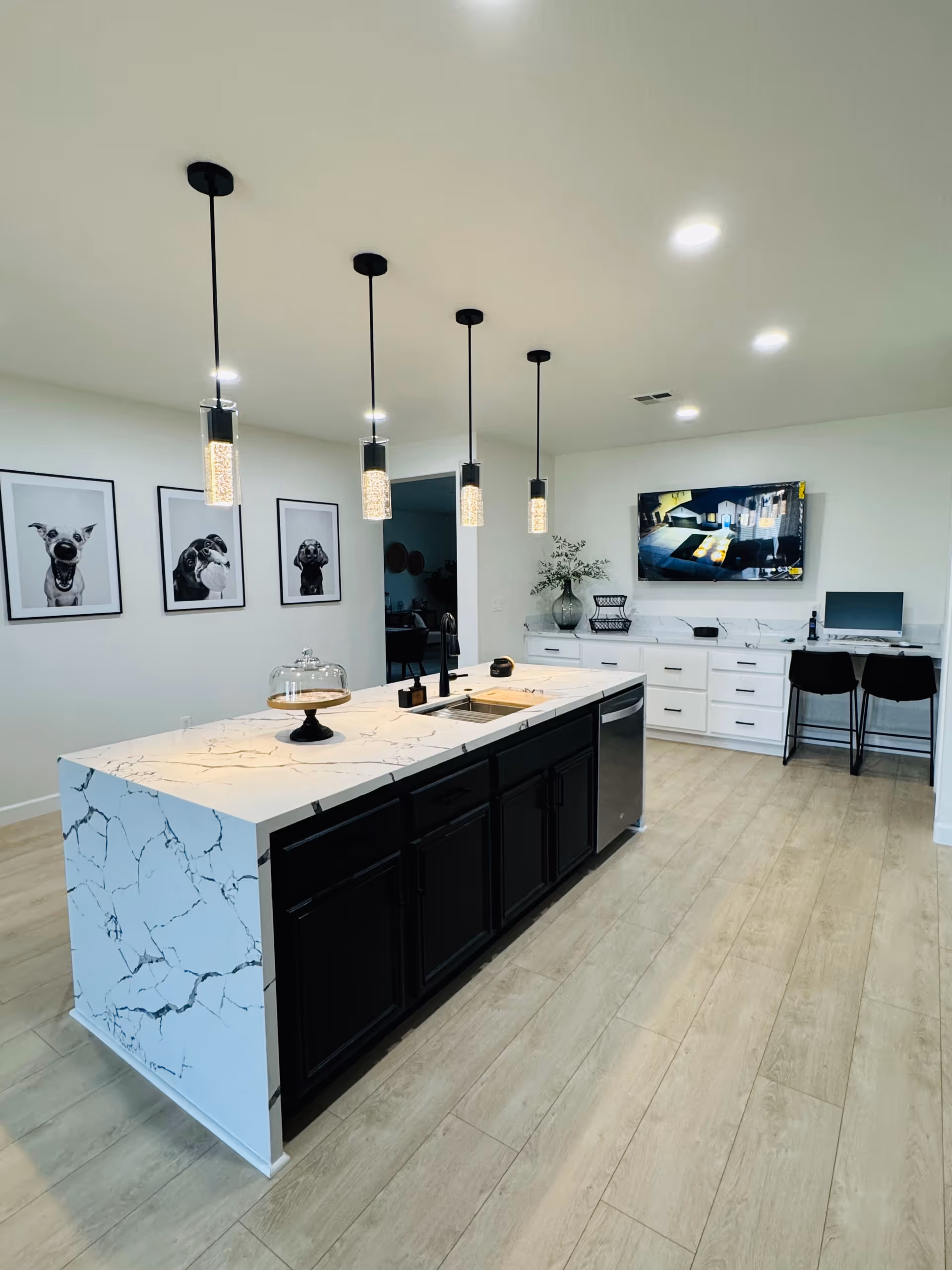Bright modern kitchen with marble island, pendant lights, and white cabinetry.