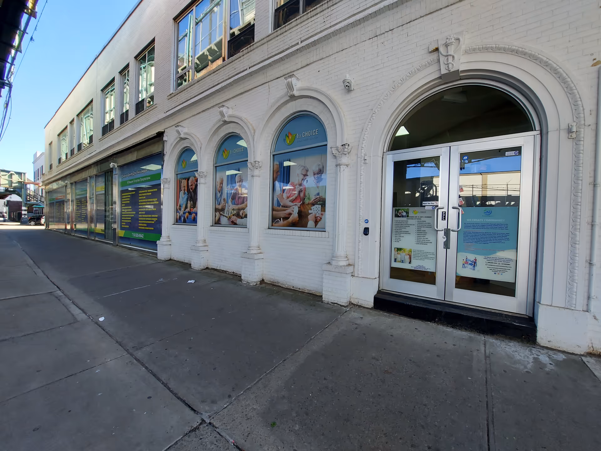 A white brick building facade with arched windows and front glass doors.