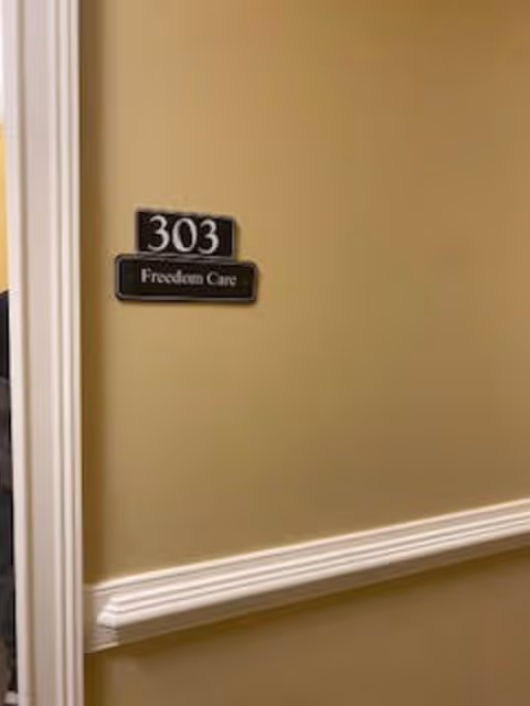 Door plaque showing 303 and Freedom Care on a beige wall.