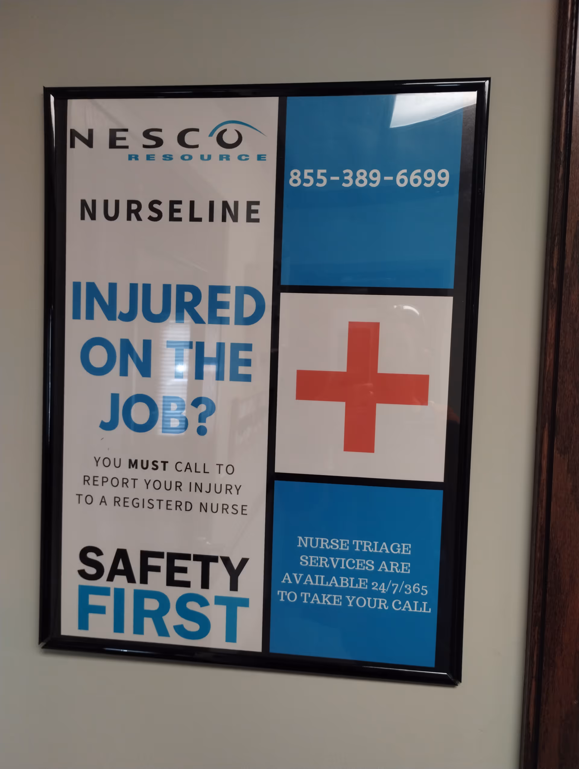 Framed safety poster on wall promotes injury reporting with blue and red cross design.