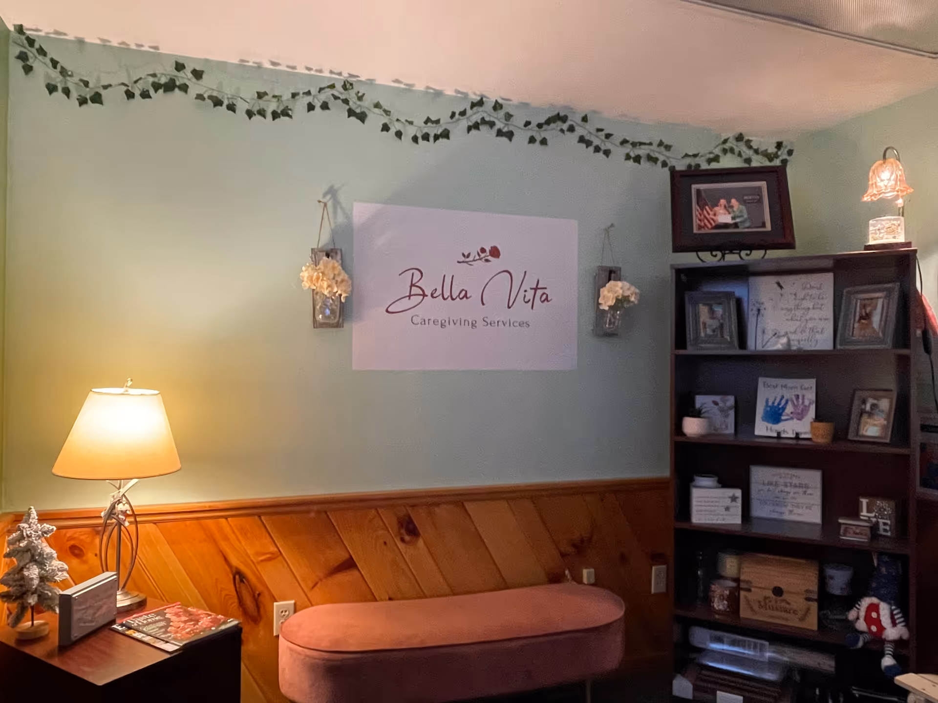 Cozy interior with a Bella Vita Caregiving Services sign on a pastel wall.