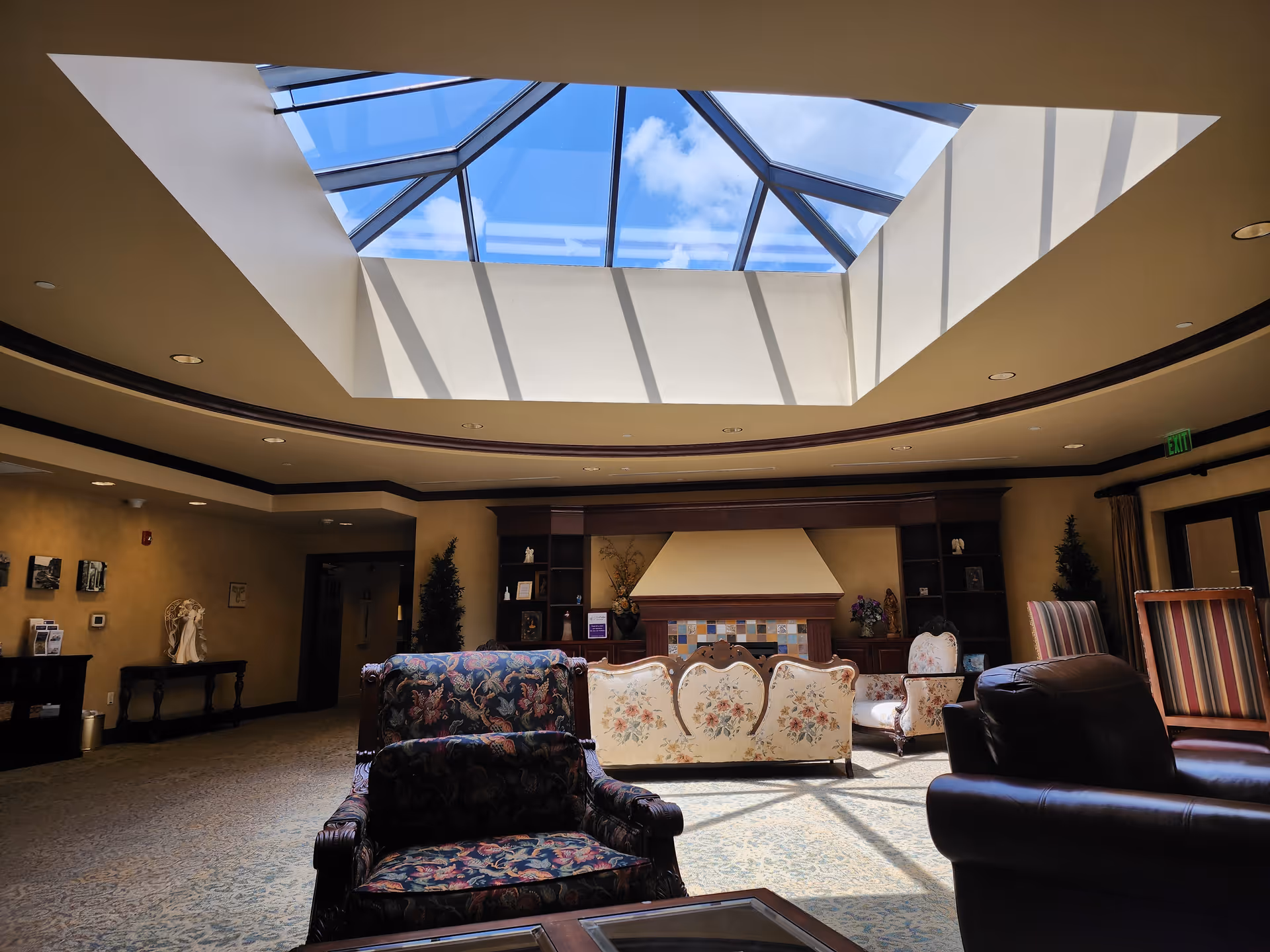 Bright skylight atrium with plush seating in a spacious senior living lobby.
