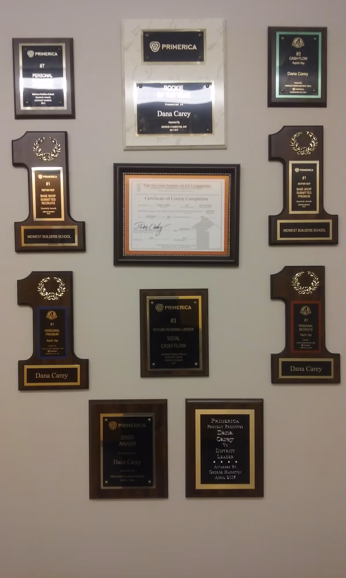 Wall adorned with numerous framed awards and a central certificate.