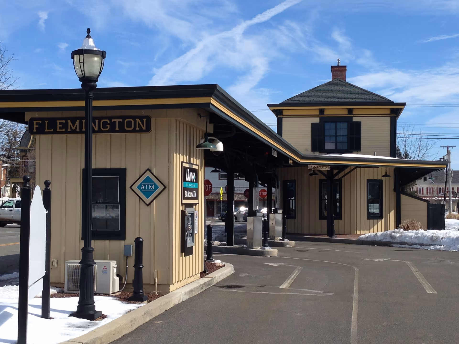 Exterior view of a beige building with Flemington sign and ATM under blue sky.