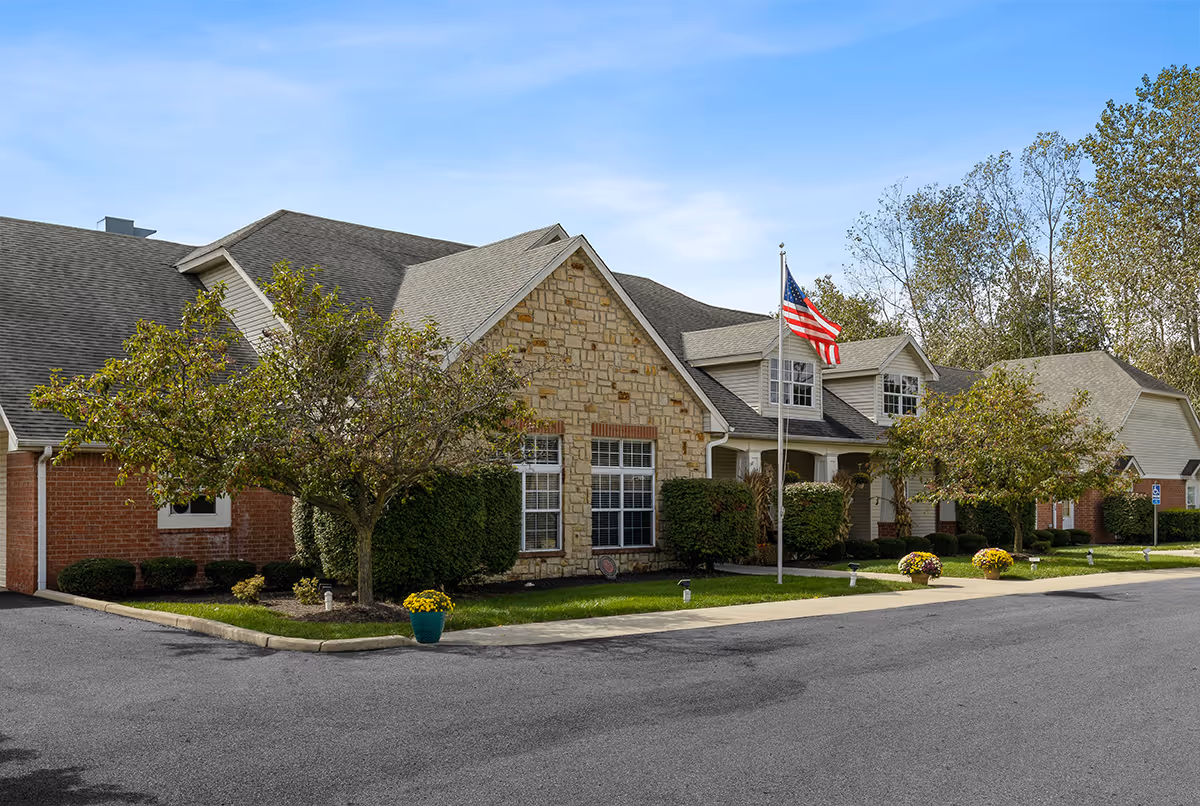 Exterior view of Trustwell Living at Urbana Place, a stone facade building with landscaped front.
