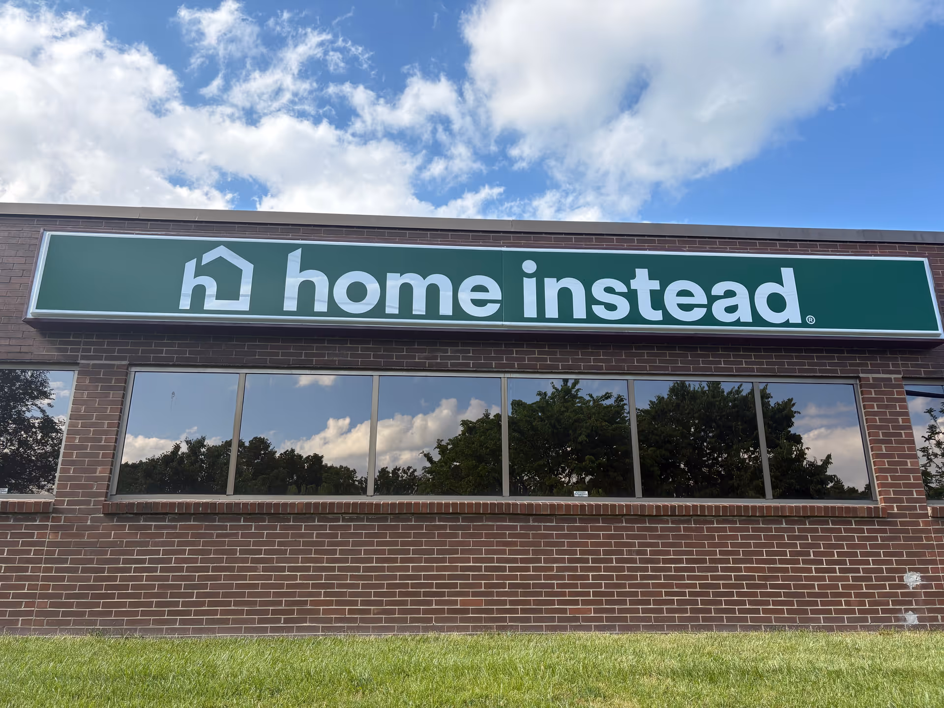 Brick building exterior with a large green 'home instead' sign.
