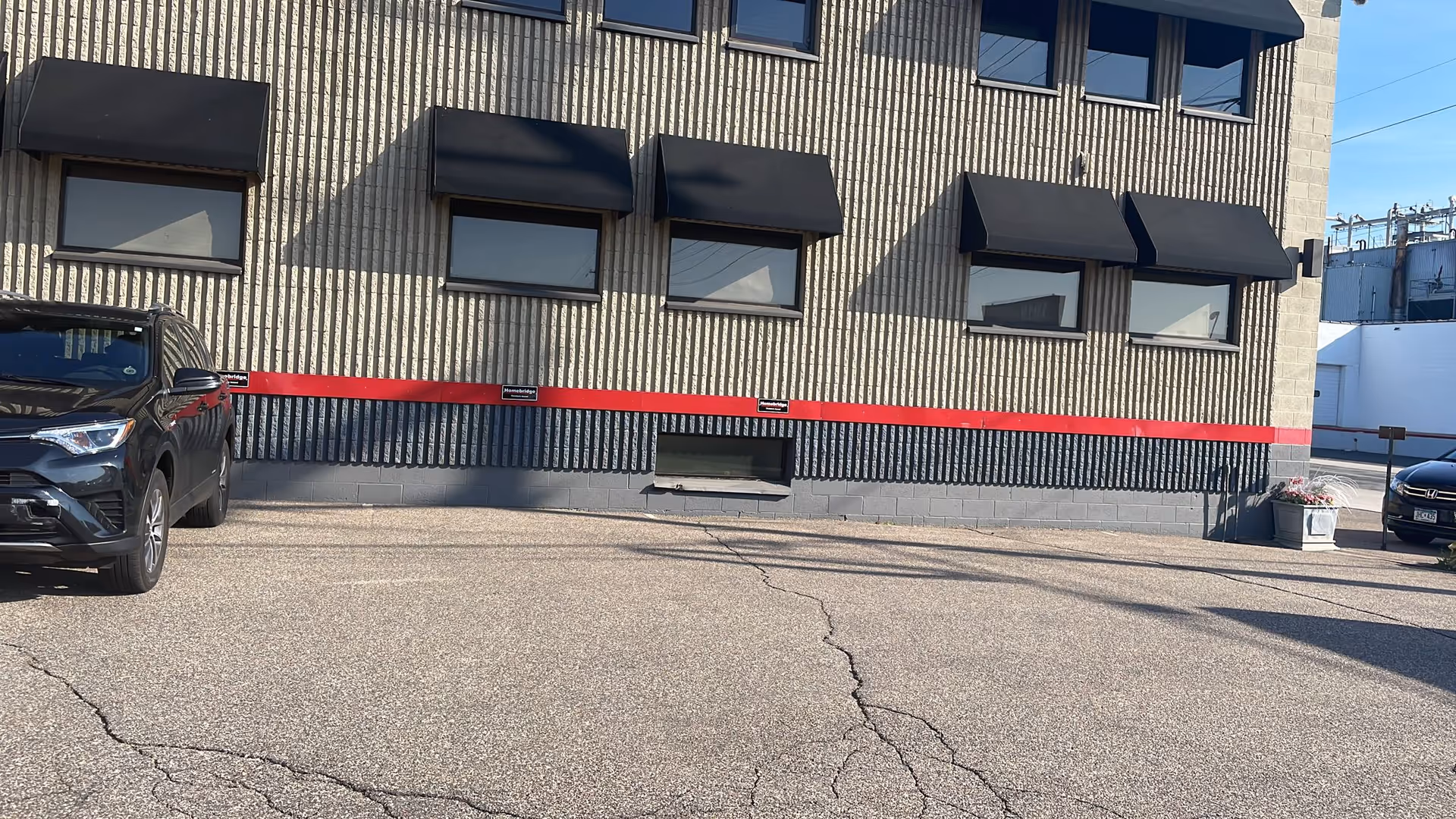 Exterior view of a building with black awnings and a red stripe.
