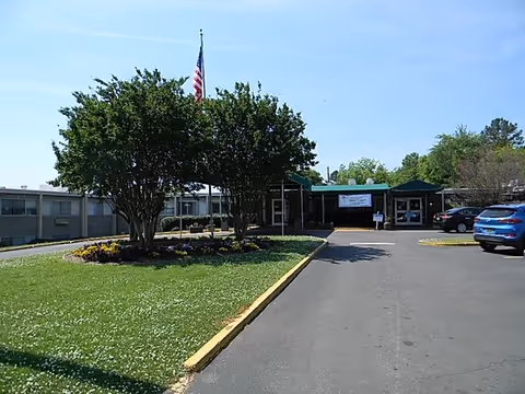 Exterior view of Blue Ridge Healthcare Birmingham with driveway, trees, entrance, and flag