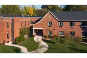 Exterior of a brick senior living building with a curved walkway and landscaped lawn.