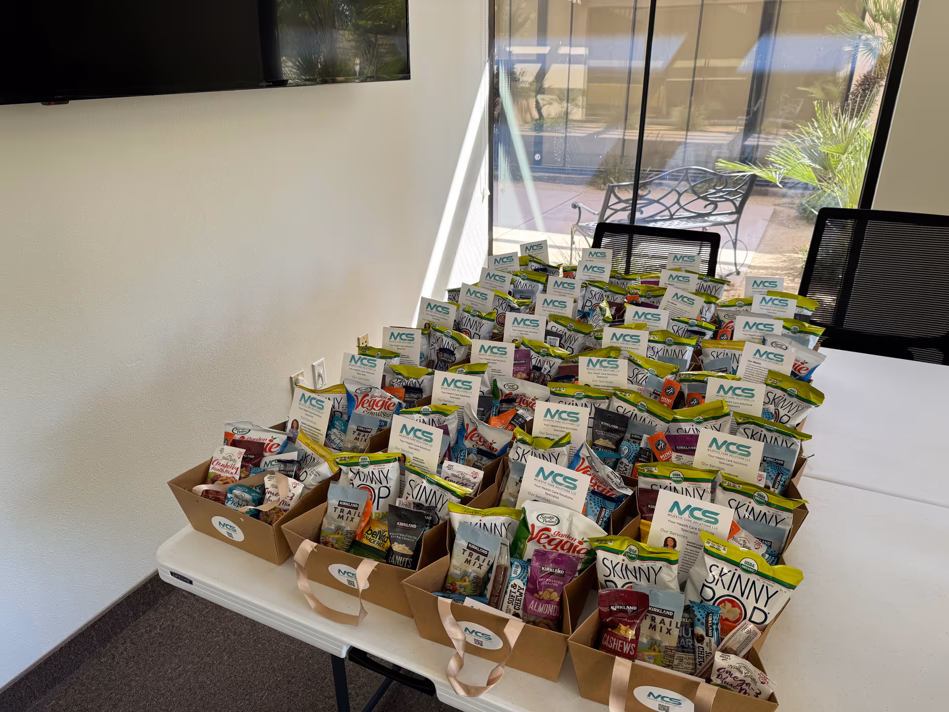 Conference table with numerous snack boxes arranged in baskets inside a bright room.