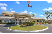 Exterior view of Buccaneer Mobile Estates front entrance with flags and palm trees.