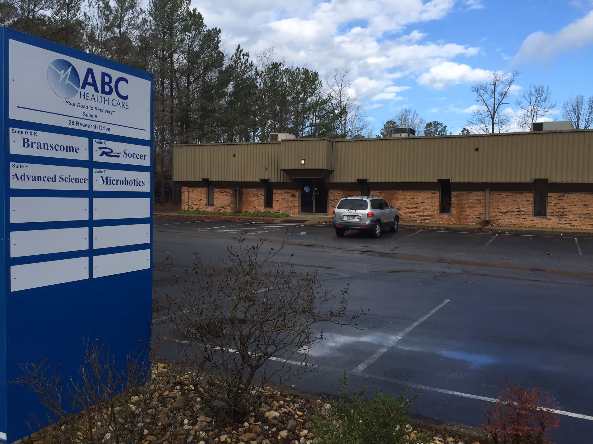 Exterior view of ABC Health Care facility with a large sign near the parking lot.