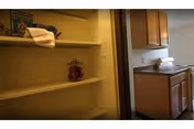 Open pantry shelves with a jar on the middle shelf and a towel on top.