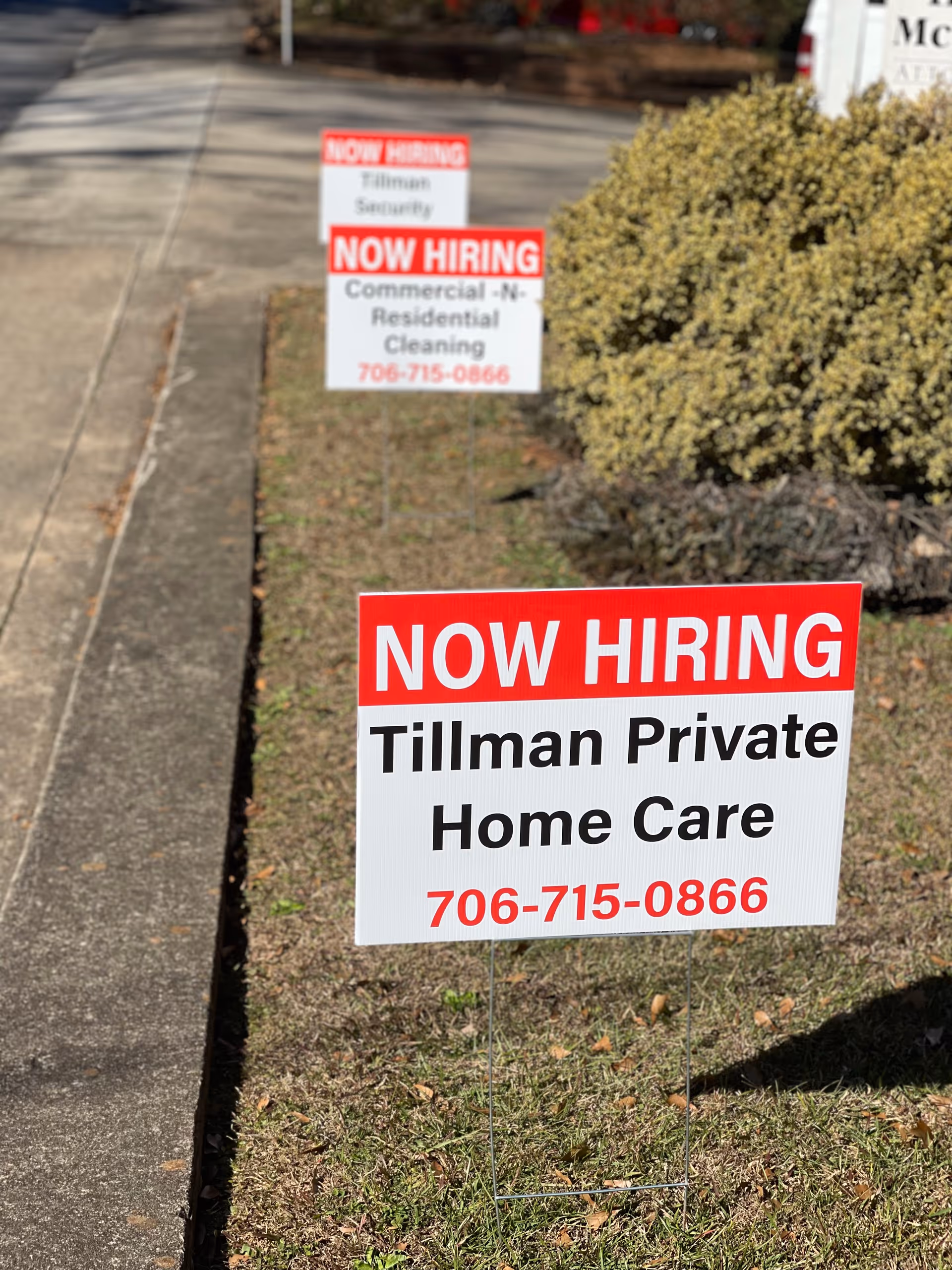 Two 'NOW HIRING' signs in a lawn, promoting Tillman Private Home Care LLC.