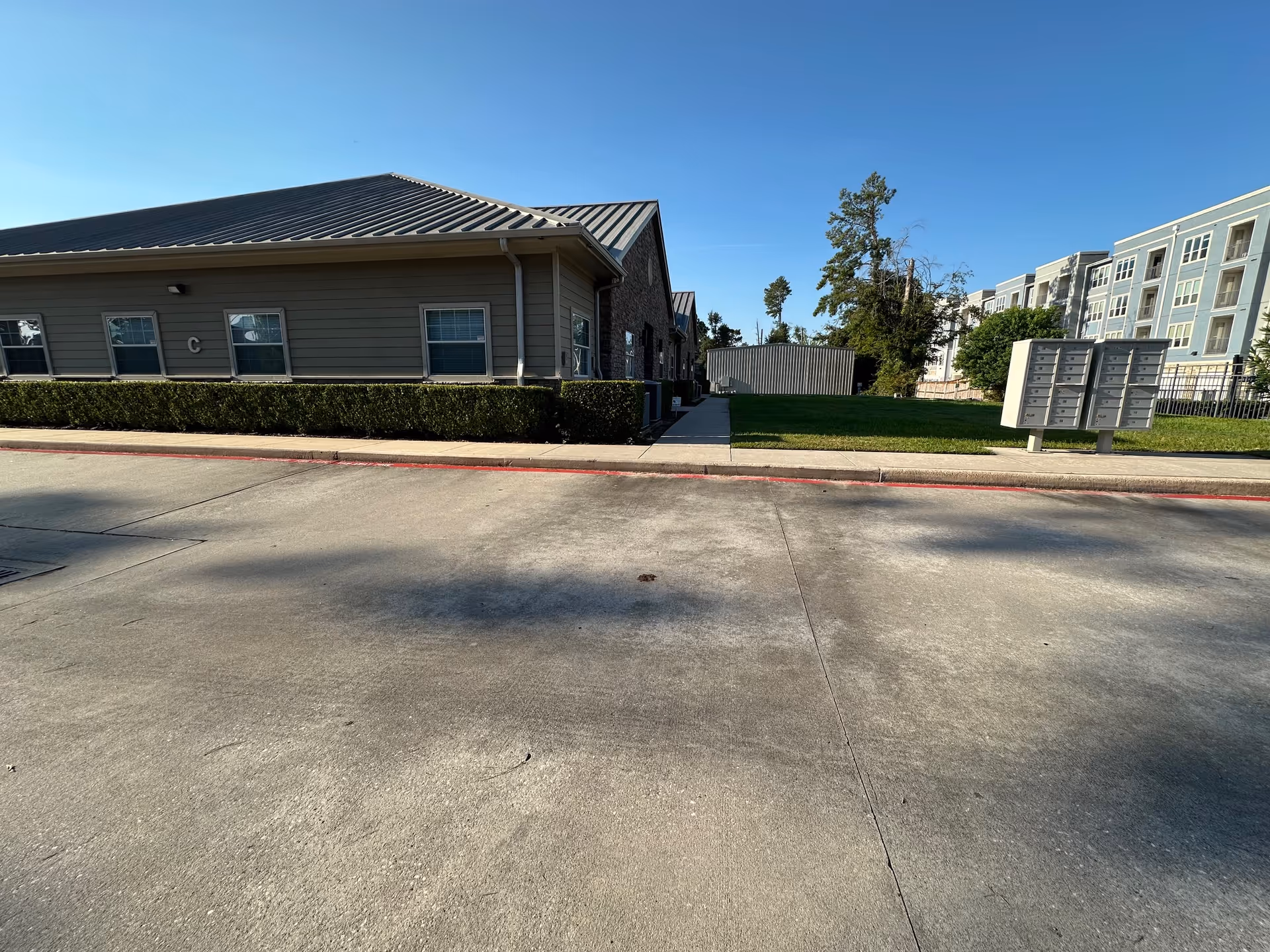 Exterior view of a senior living building with lawn, sidewalk, and mailboxes.