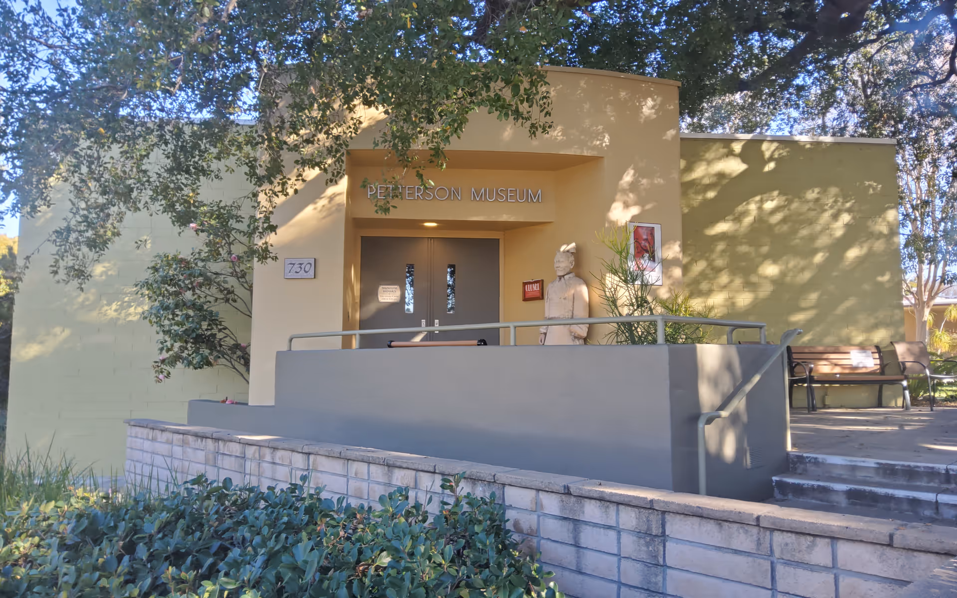 Front view of a pale building entrance with a ramp and a museum sign.
