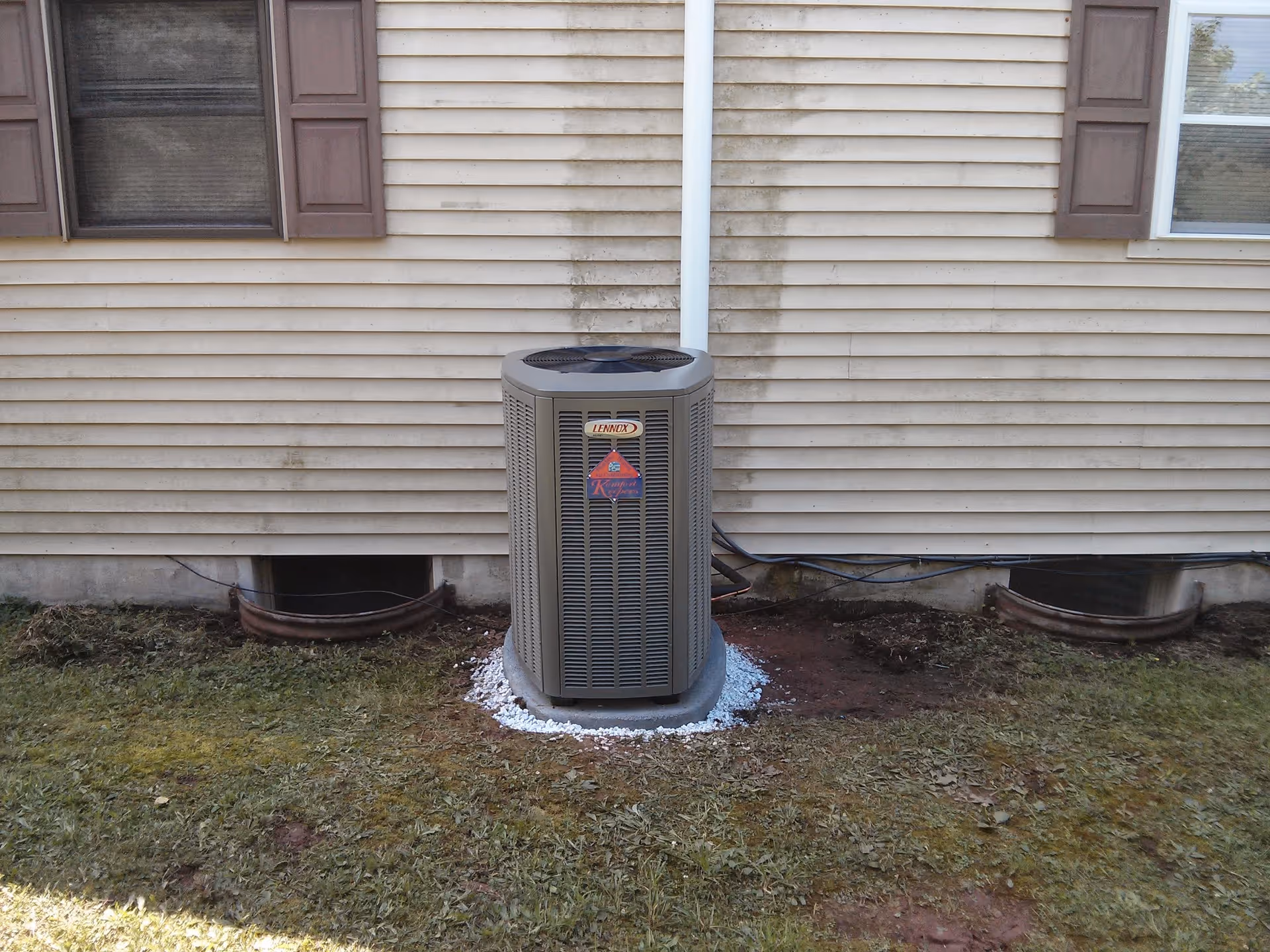 Exterior of beige siding house with a central air conditioning unit outside.