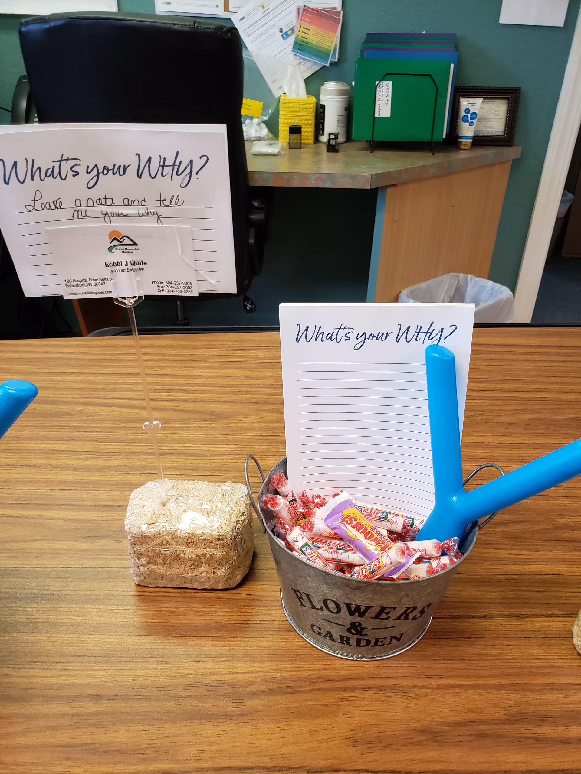 Front desk area with signs, candy bucket, and office supplies inside a facility.