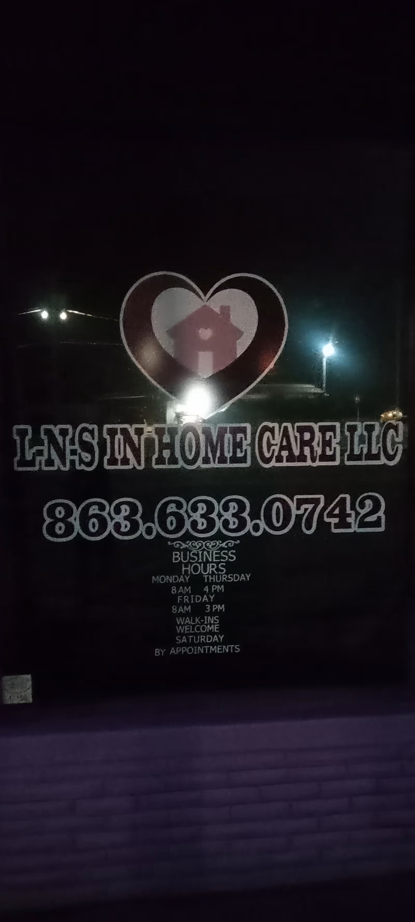 Night exterior of L-N-S In Home Care LLC building with sign and phone number