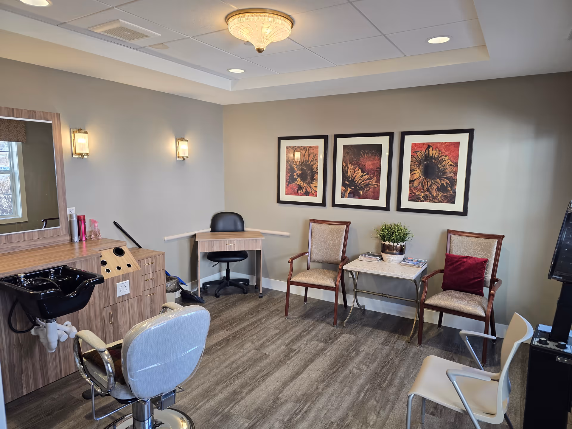 Hair salon area in Meadow Place Assisted Living with washing station, chairs, and framed art.