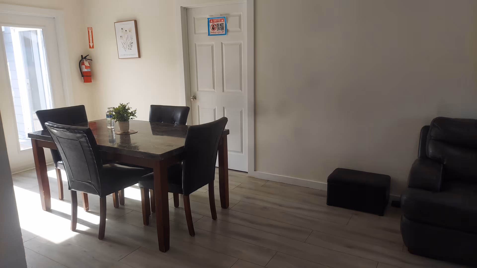 Interior dining area with a dark wooden table, six chairs, plant centerpiece, and nearby sofa.