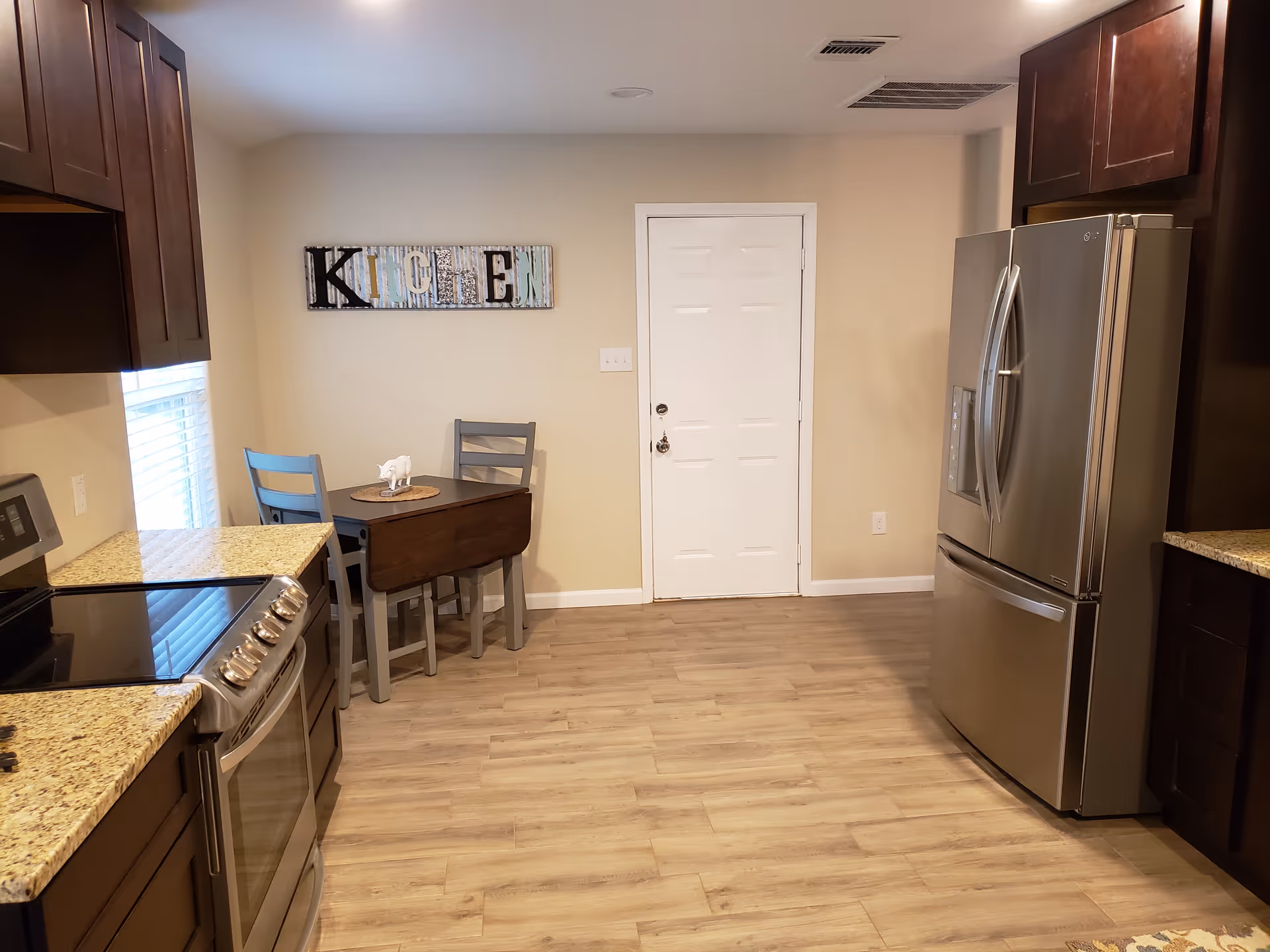 Modern kitchen with stainless steel appliances, granite countertops, and a small dining table.