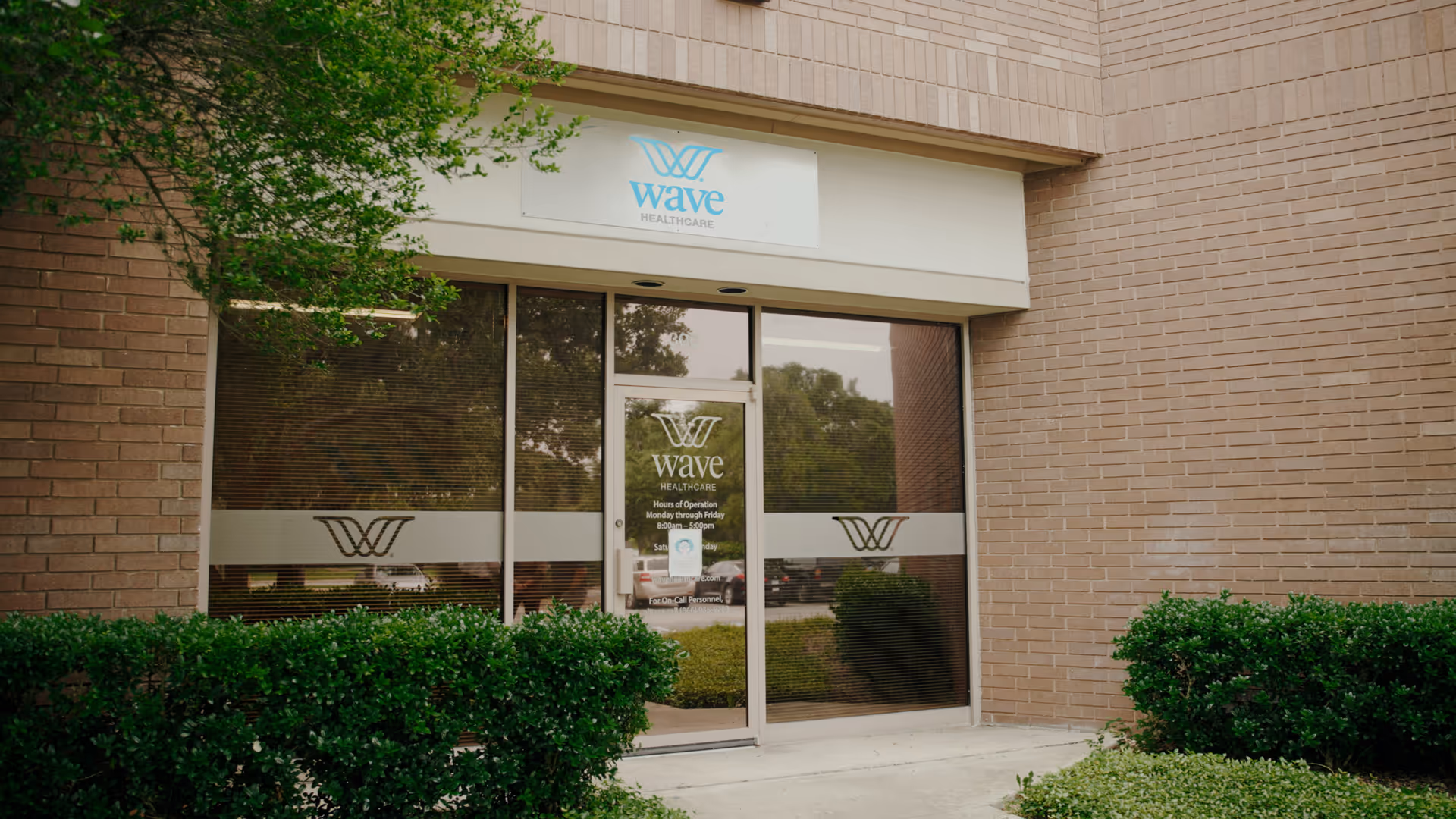 Exterior view of Wave Healthcare entrance with glass doors and brick walls.