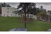 Exterior view of Envoy Of Staunton senior living facility with green lawn and entrance.