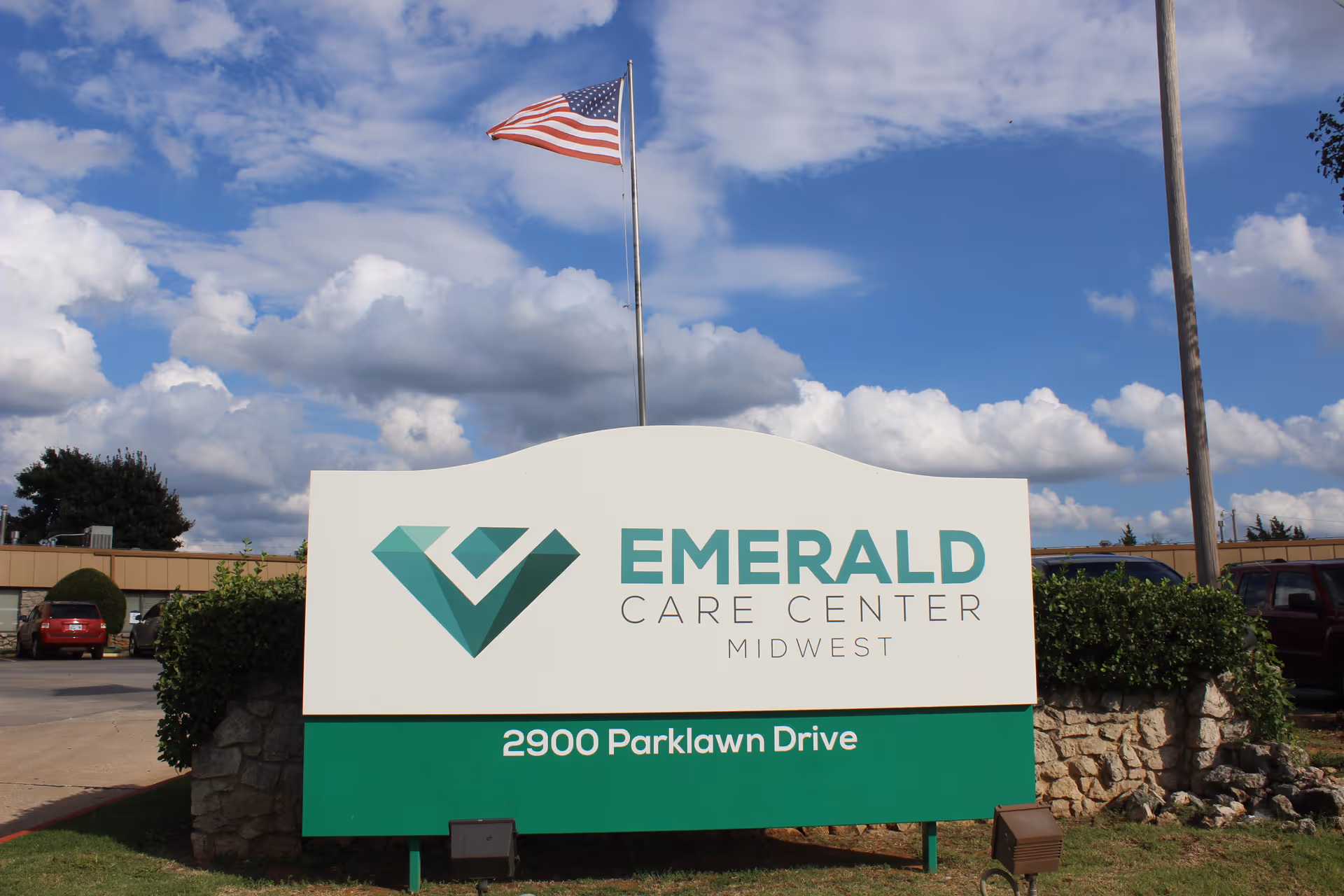 Large outdoor sign reading "Emerald Care Center Midwest" with the address 2900 Parklawn Drive and an American flag overhead.