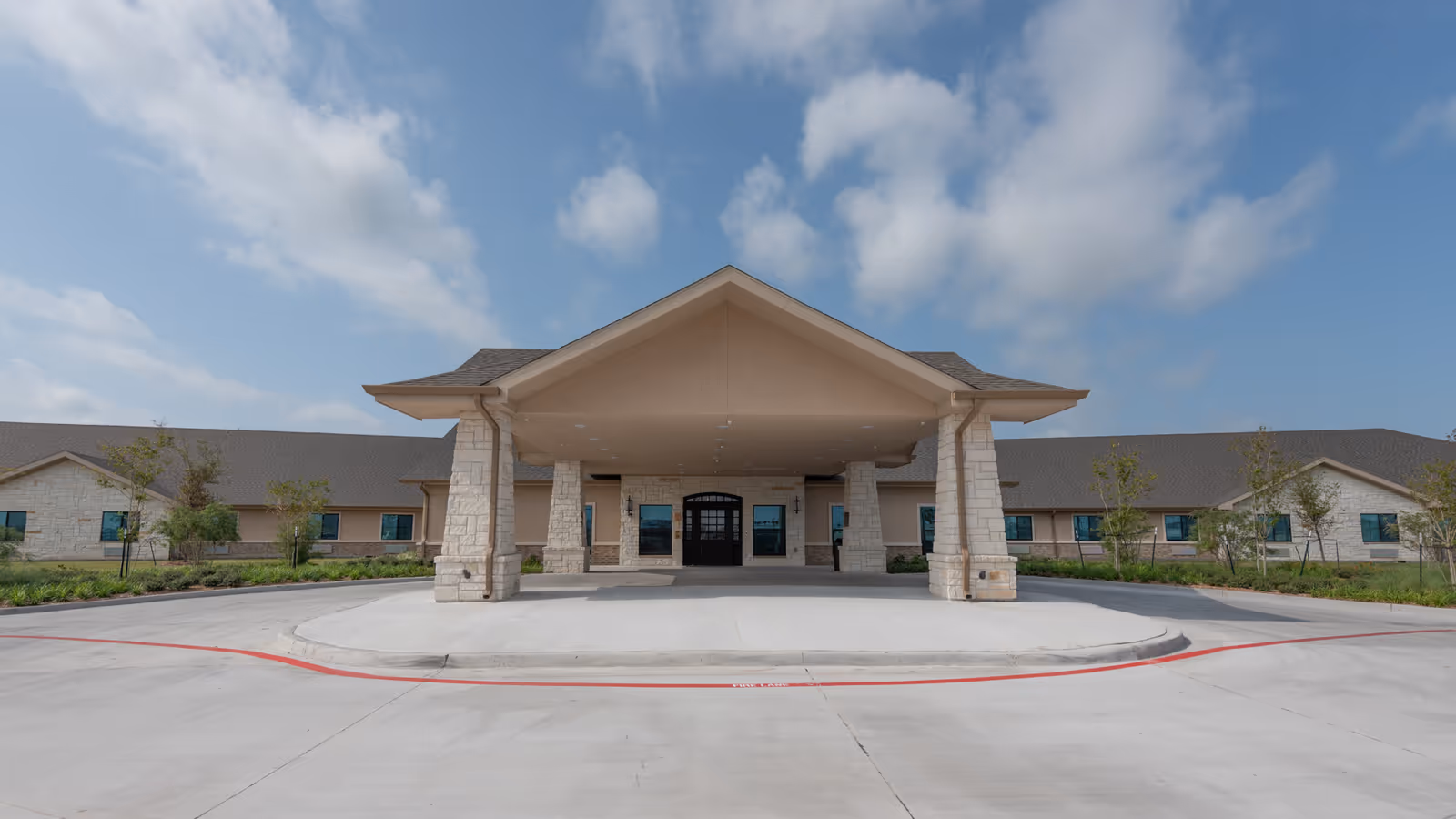 Exterior view of a single-story medical facility with a large covered entrance and stone columns.