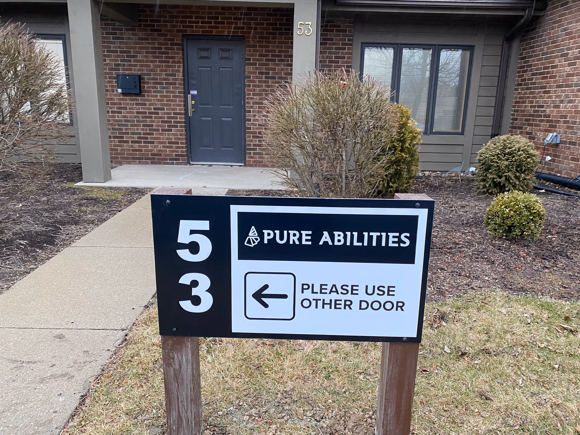 Front of a brick building with a Pure Abilities sign directing to the other door.
