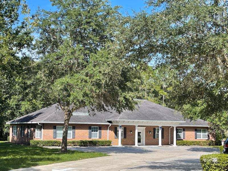 Single-story brick senior living facility entrance with white columns and a concrete driveway.