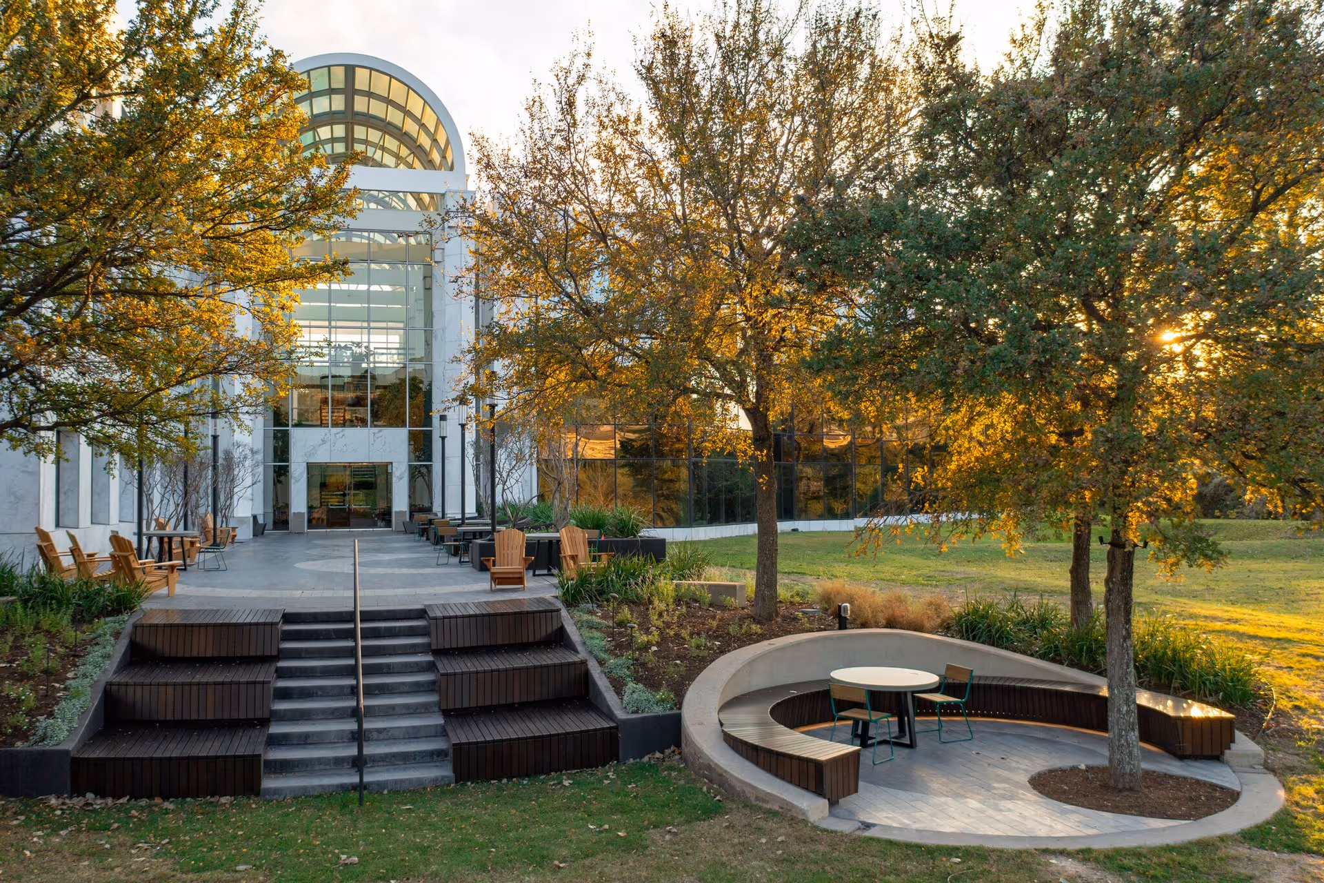 Modern senior living facility exterior with glass entrance and circular outdoor seating area.