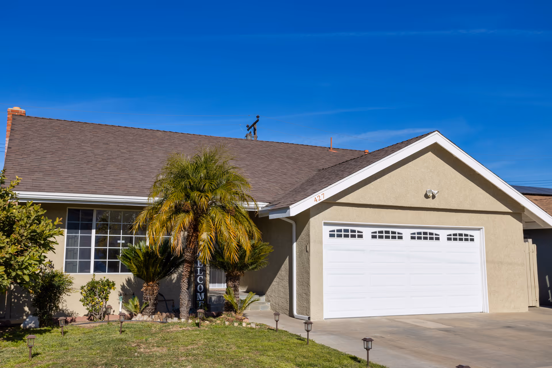 Front view of a beige single-story home with a two-car garage and landscaping.