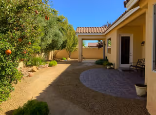 Sunny outdoor courtyard of Bella Vita Care Home with a covered patio and orange trees.