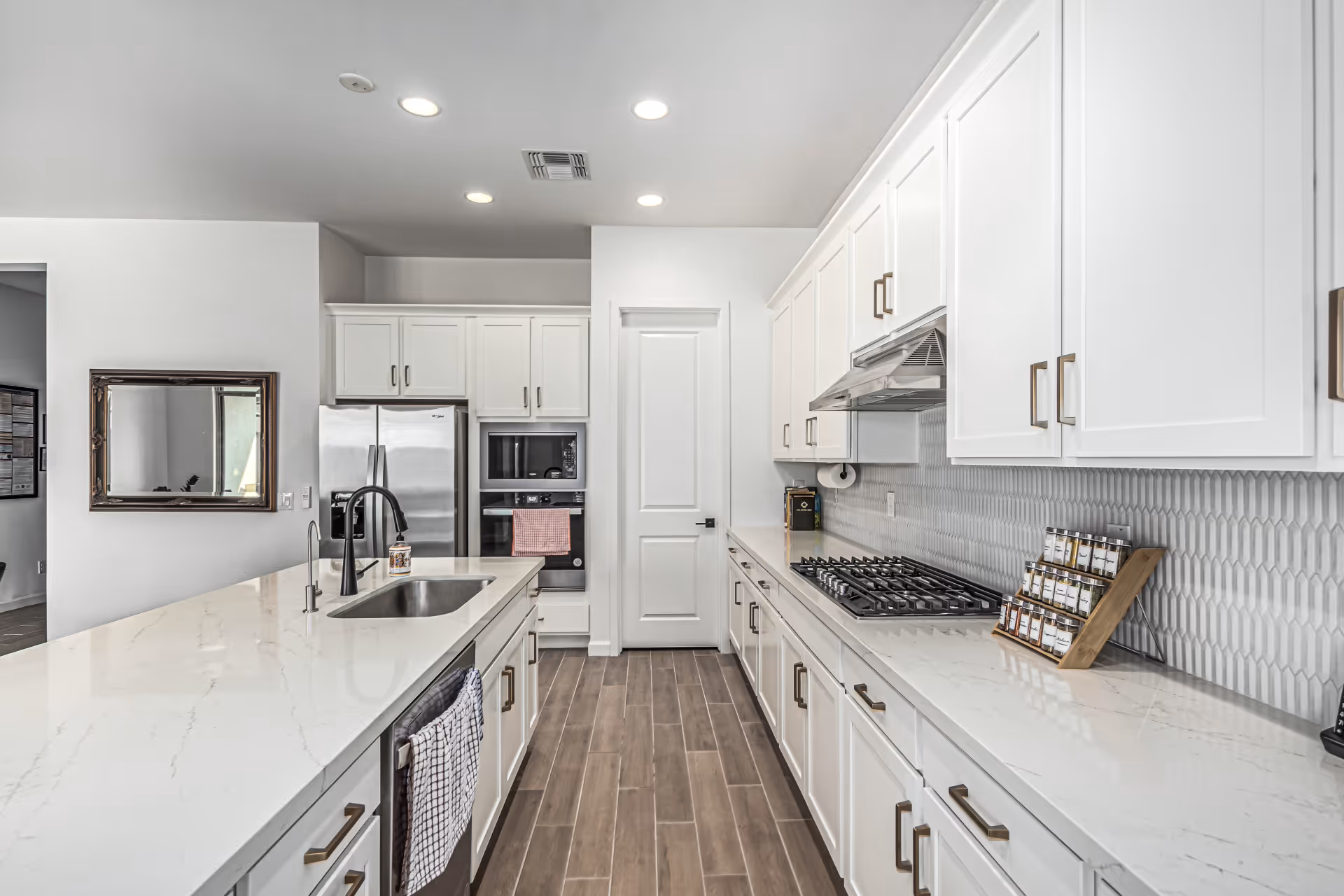 Bright, modern kitchen with white cabinets, island sink, stainless appliances, and tile floor.