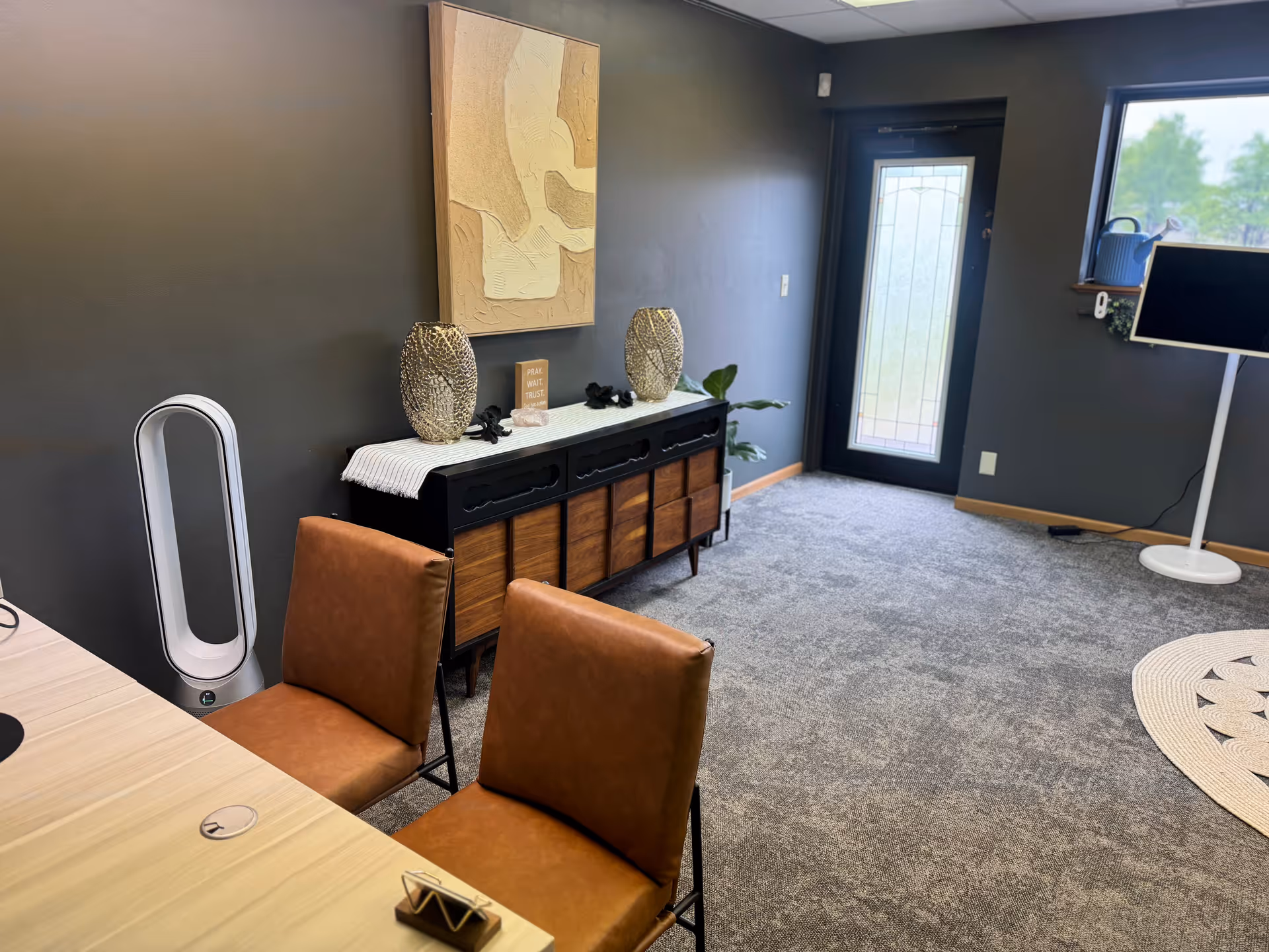 Interior lounge with brown leather chairs, a console table, doorway, and TV.