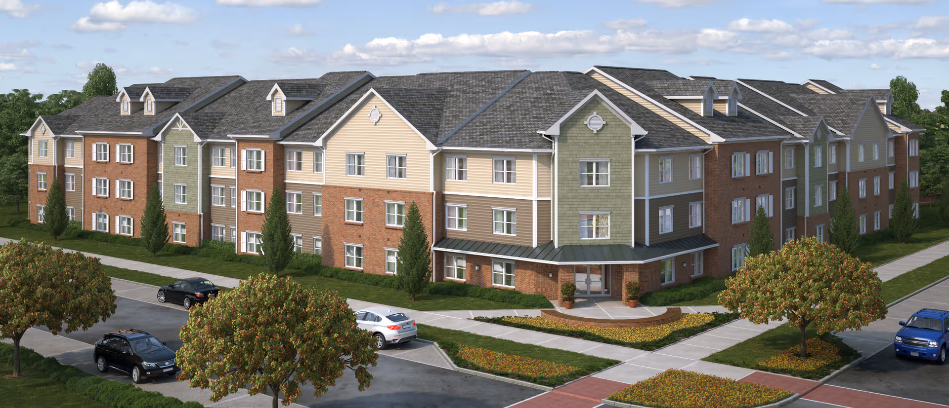 A multi-wing senior living building with brick and siding, surrounded by trees and parked cars.