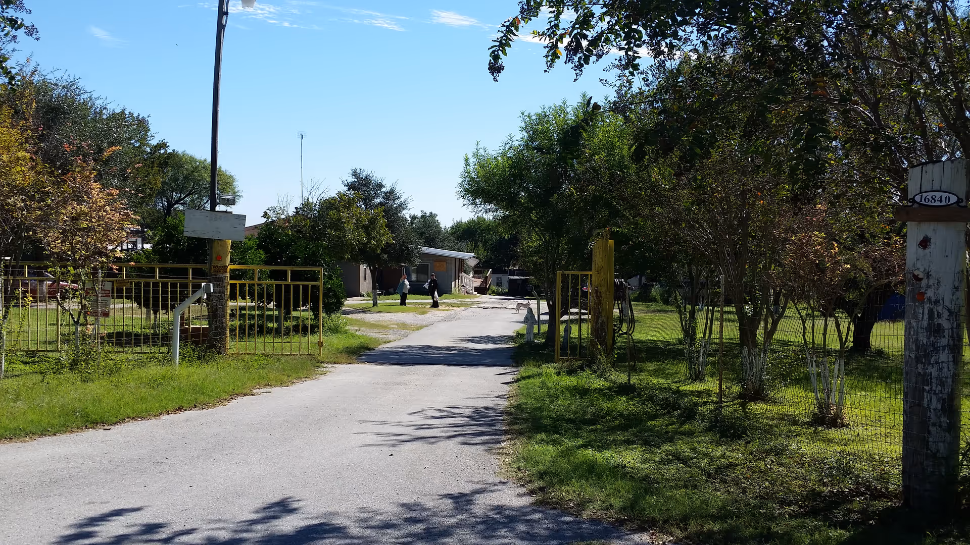 Exterior view of Longoria's Personal Care Home with gate, trees, and road.