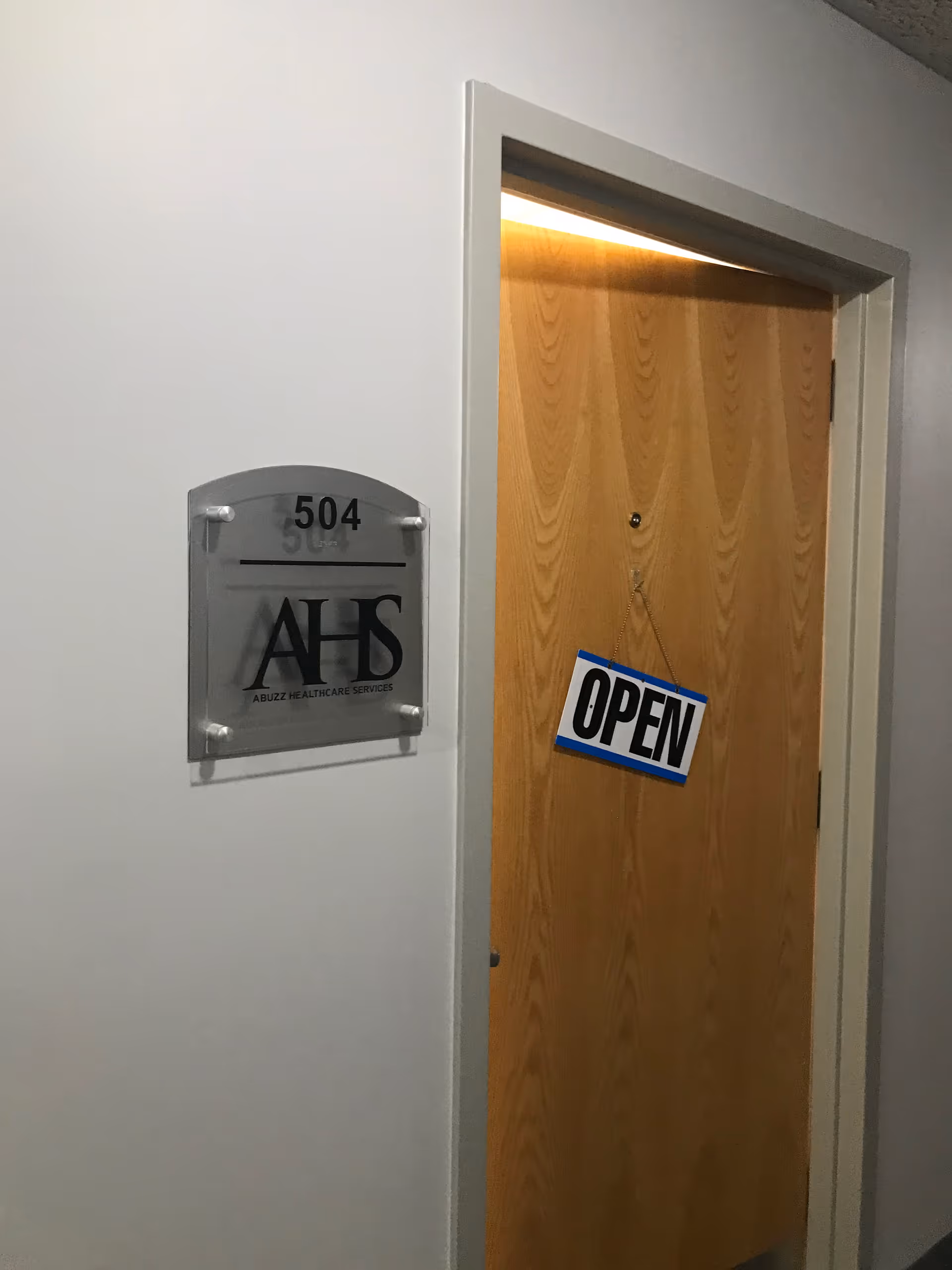 Door labeled 504 with OPEN sign in a hallway near a gray AHS plaque.