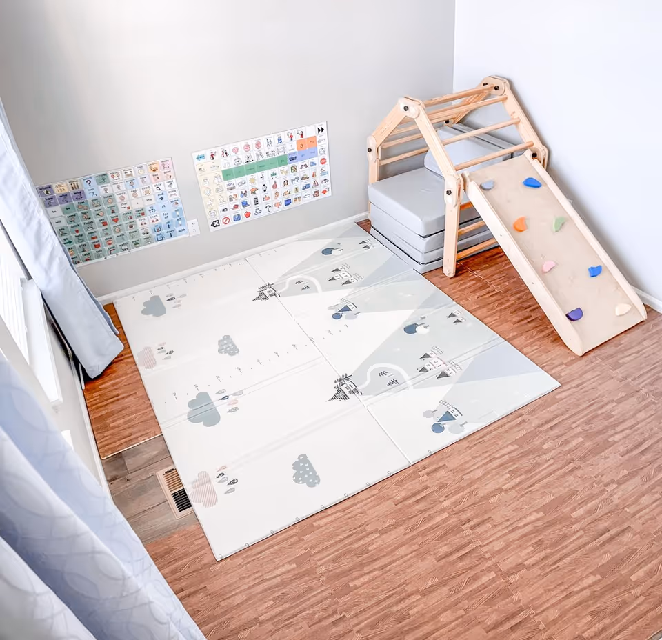Indoor therapy room with a climbing ramp, mats, and wall charts.