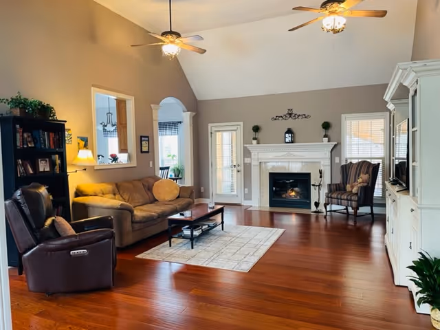 Cozy living room with sofa, armchairs, coffee table, and a fireplace in Serenity Place.