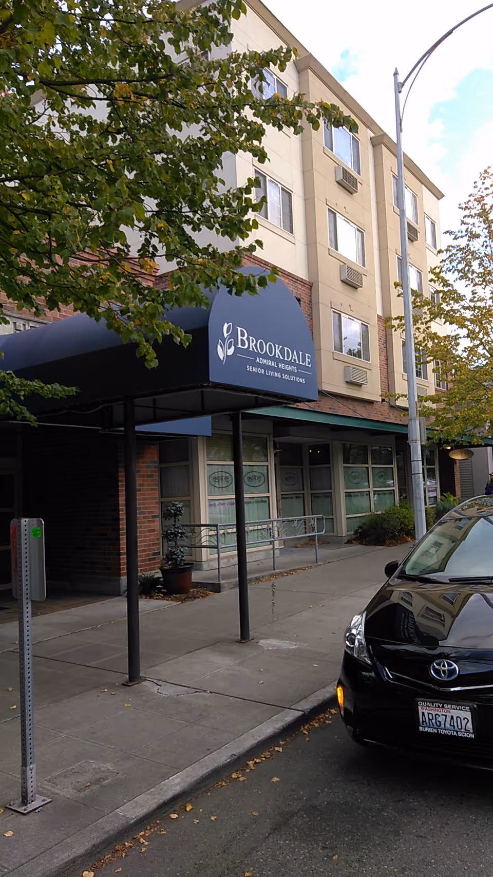 Exterior view of Brookdale Admiral Heights building with blue awning and entrance.