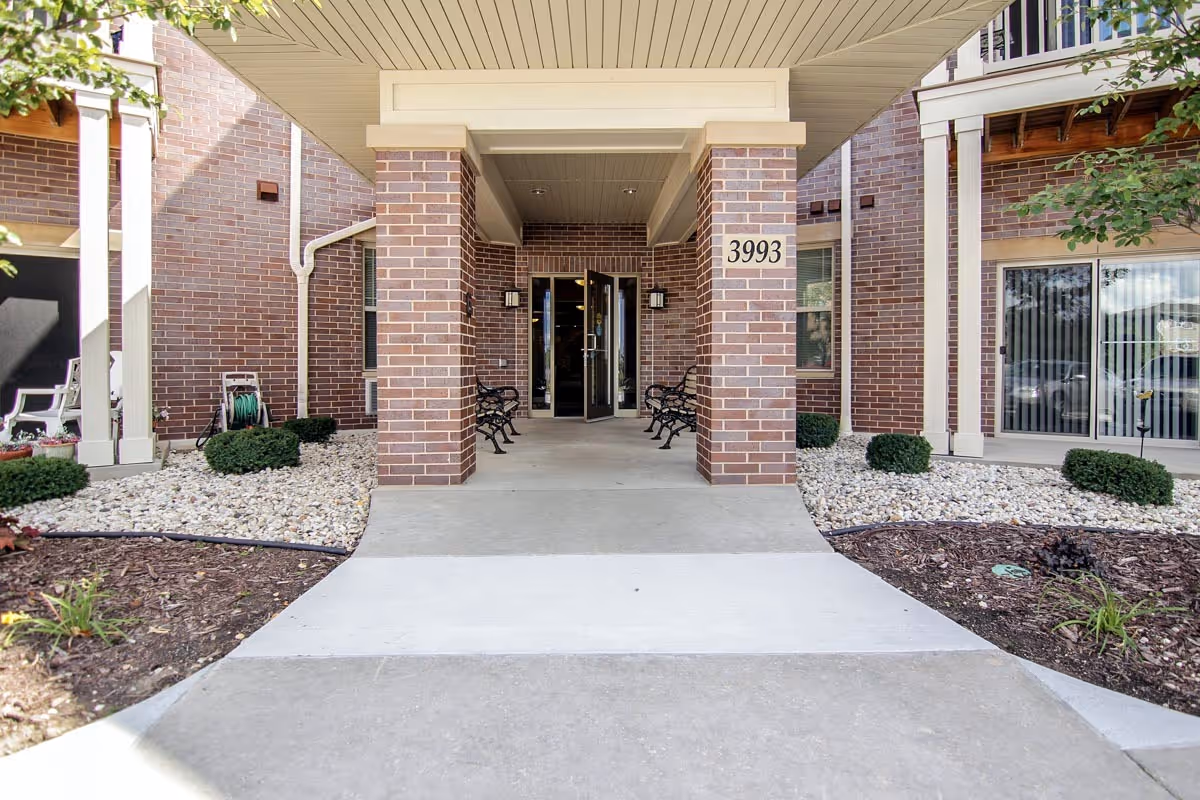 Hillcrest Apartments entrance with brick columns, benches, and a covered doorway.
