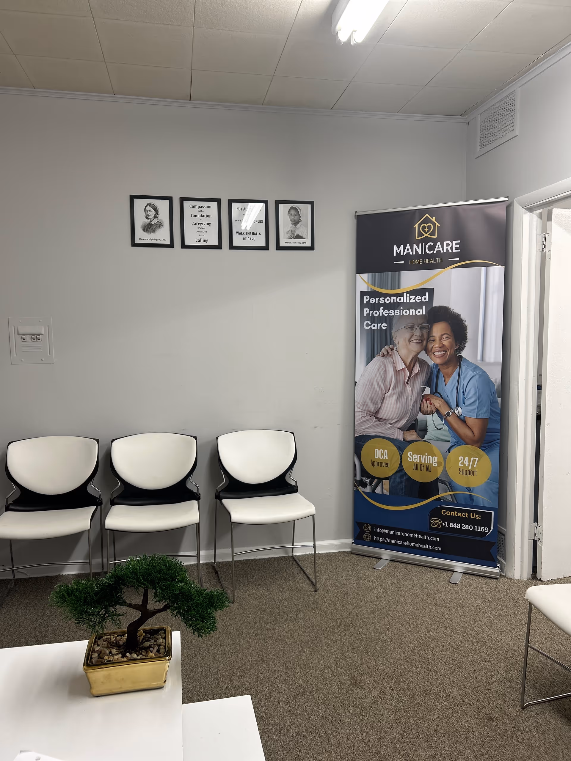 Interior waiting area with white chairs, a banner, and small bonsai plant.