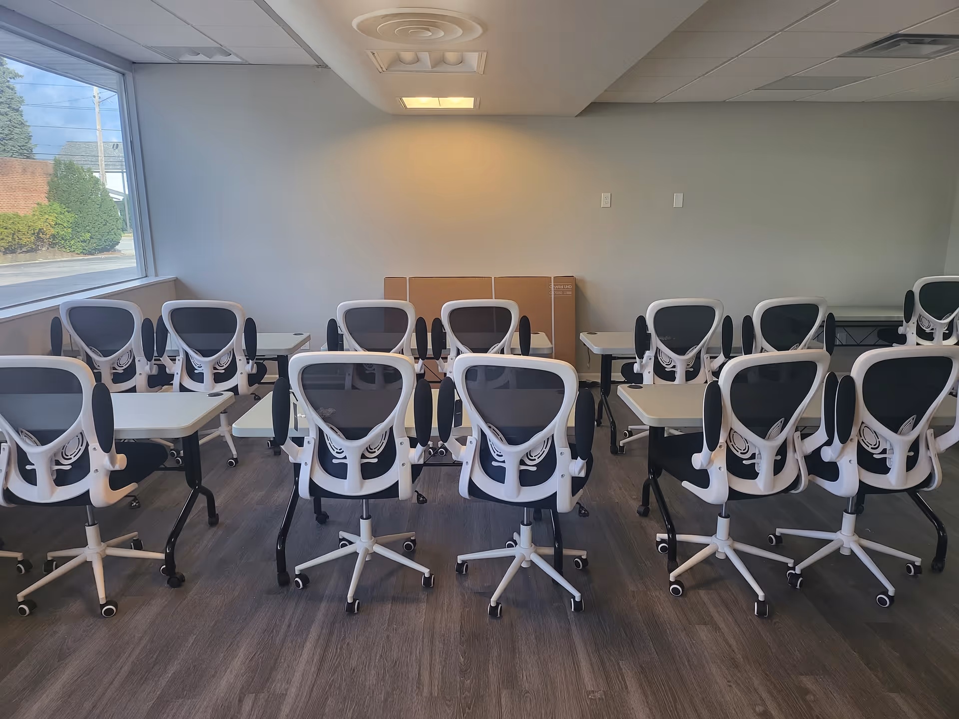 Row of white swivel chairs and desks arranged in a modern indoor classroom setting.