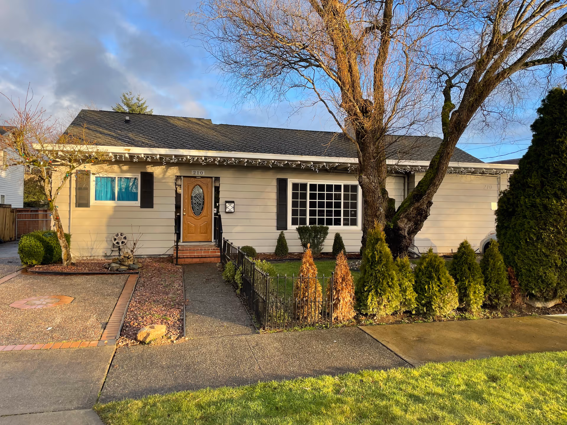 Front exterior of A Journey of Hope Adult Family Home with trees and shrubs.