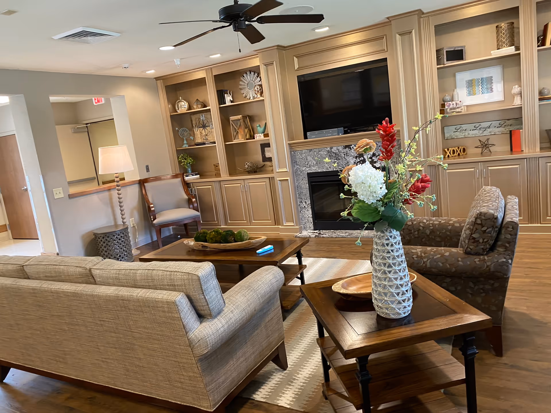 Cozy living room in a senior facility with fireplace, cabinets, TV, and seating.