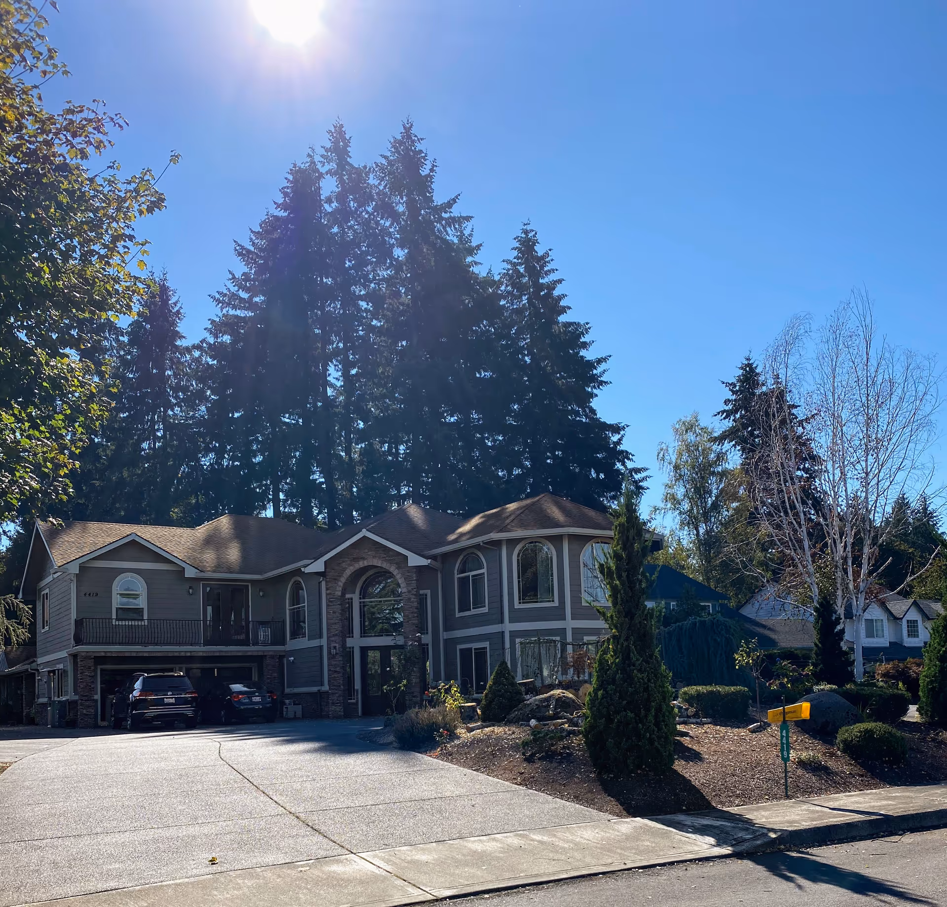 Exterior of Serenity AFH LLC senior living facility with driveway, cars, and tall trees.