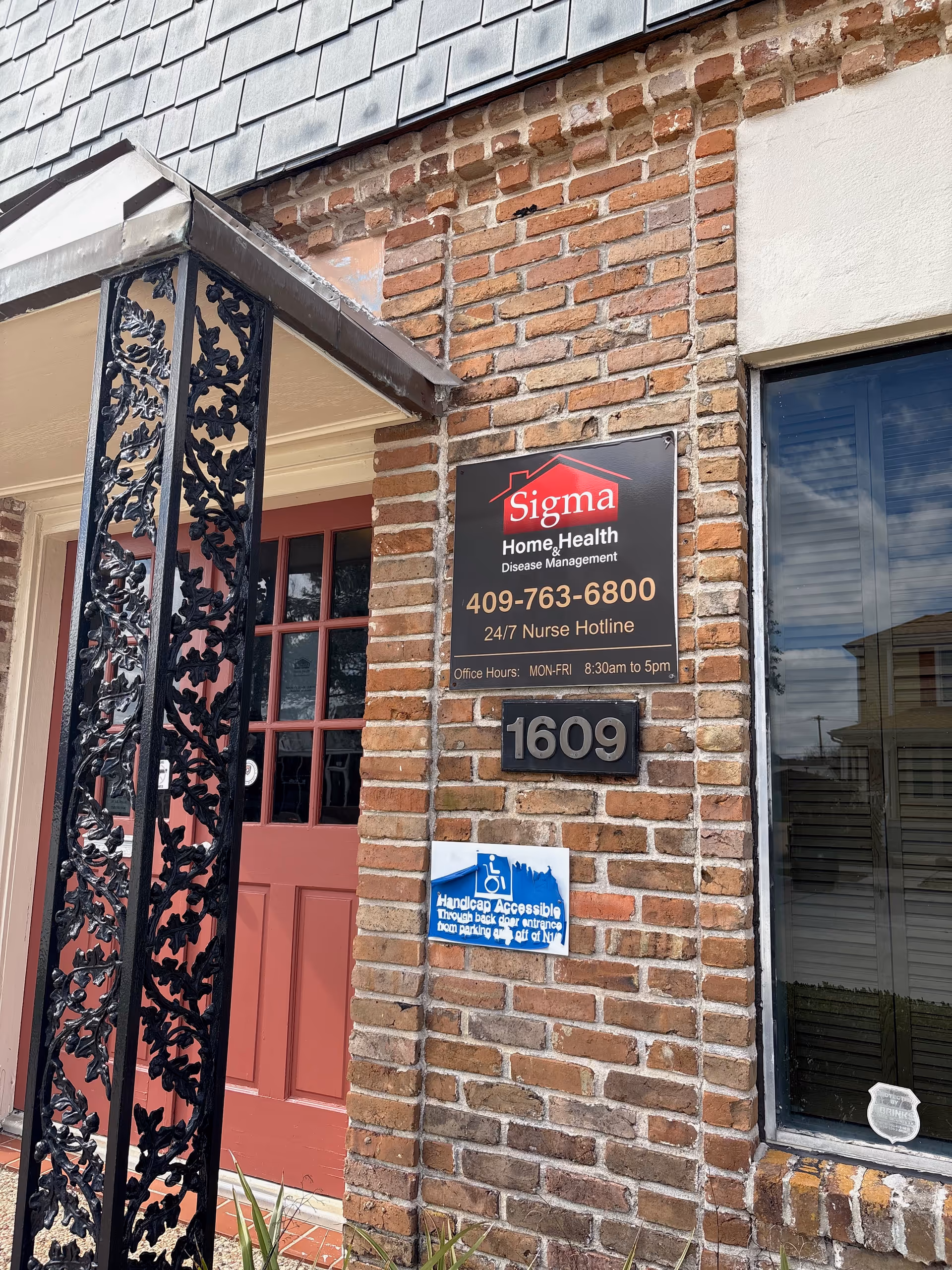 Red door and Sigma Home Health sign on a brick building entrance.